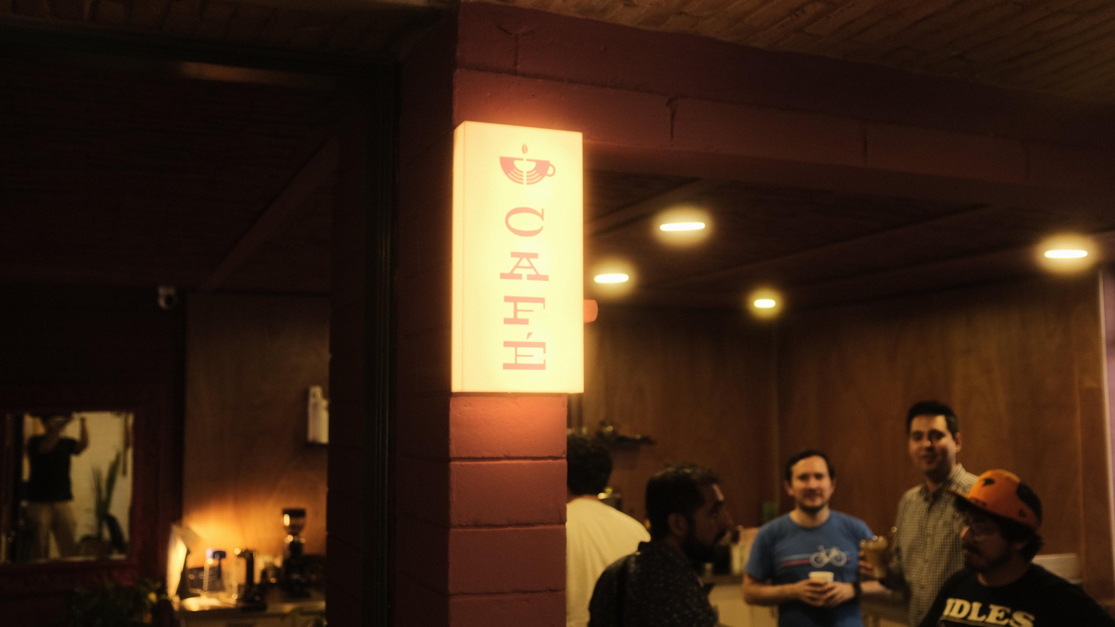 Cafe neon sign and builders gathering at Cafe Cursor Culiacán