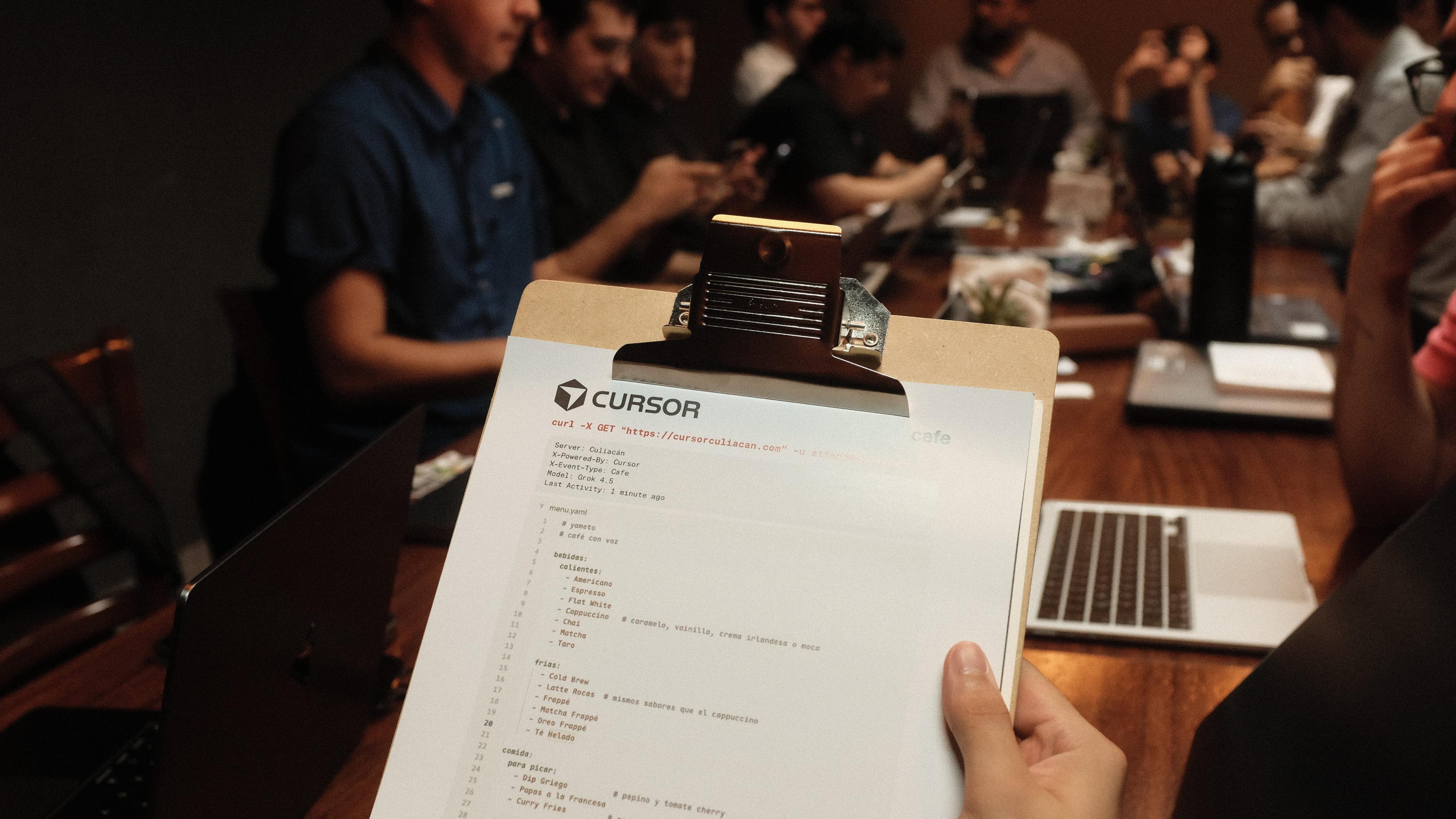 Cafe Cursor menu printout on a clipboard with builders at tables in Culiacán